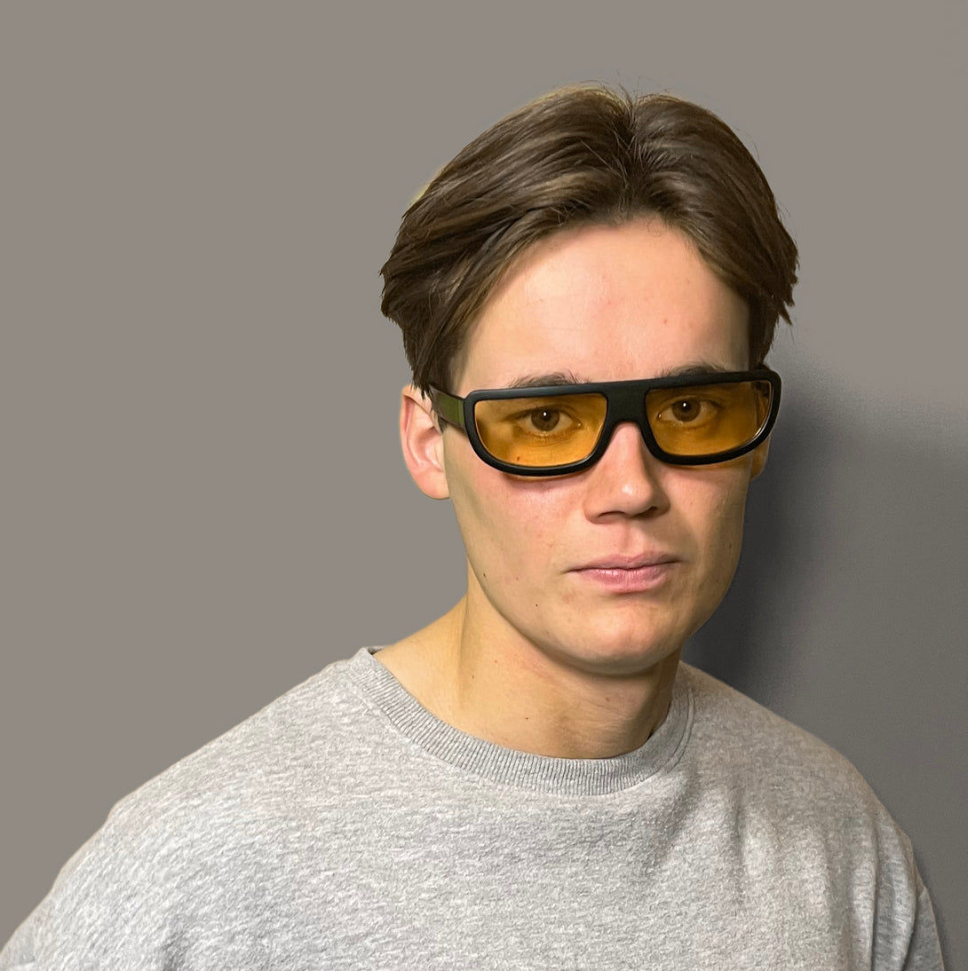 Male model - Feisty sunglasses in matt black featuring a utilitarian, straight top line frame and yellow UV400 lenses. The finishing touch to every outfit while protecting your eyes. 