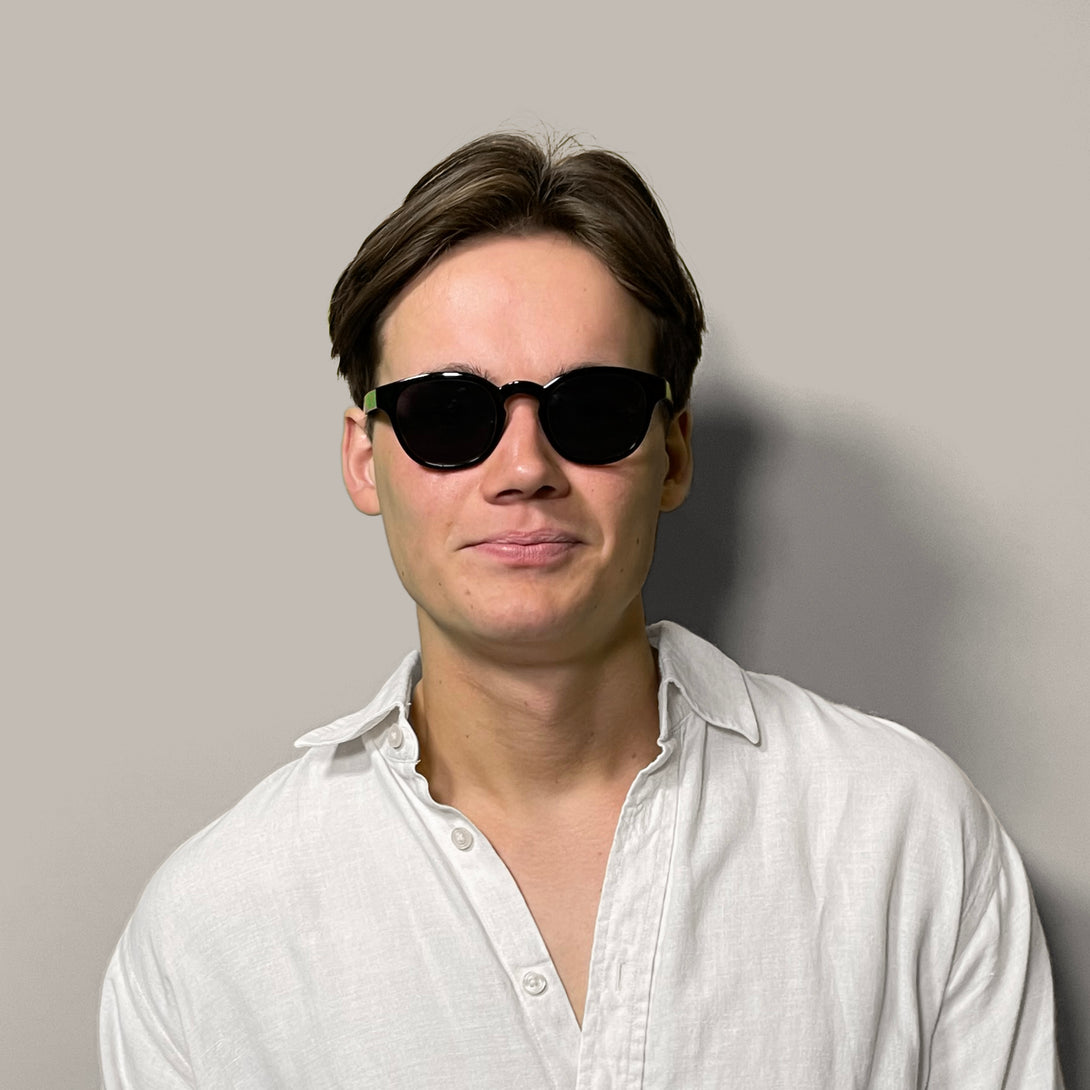 Male model - Monalux sunglasses in gloss black featuring a the classic Oxford, rounded frame and black UV400 lenses. The perfect accessory.