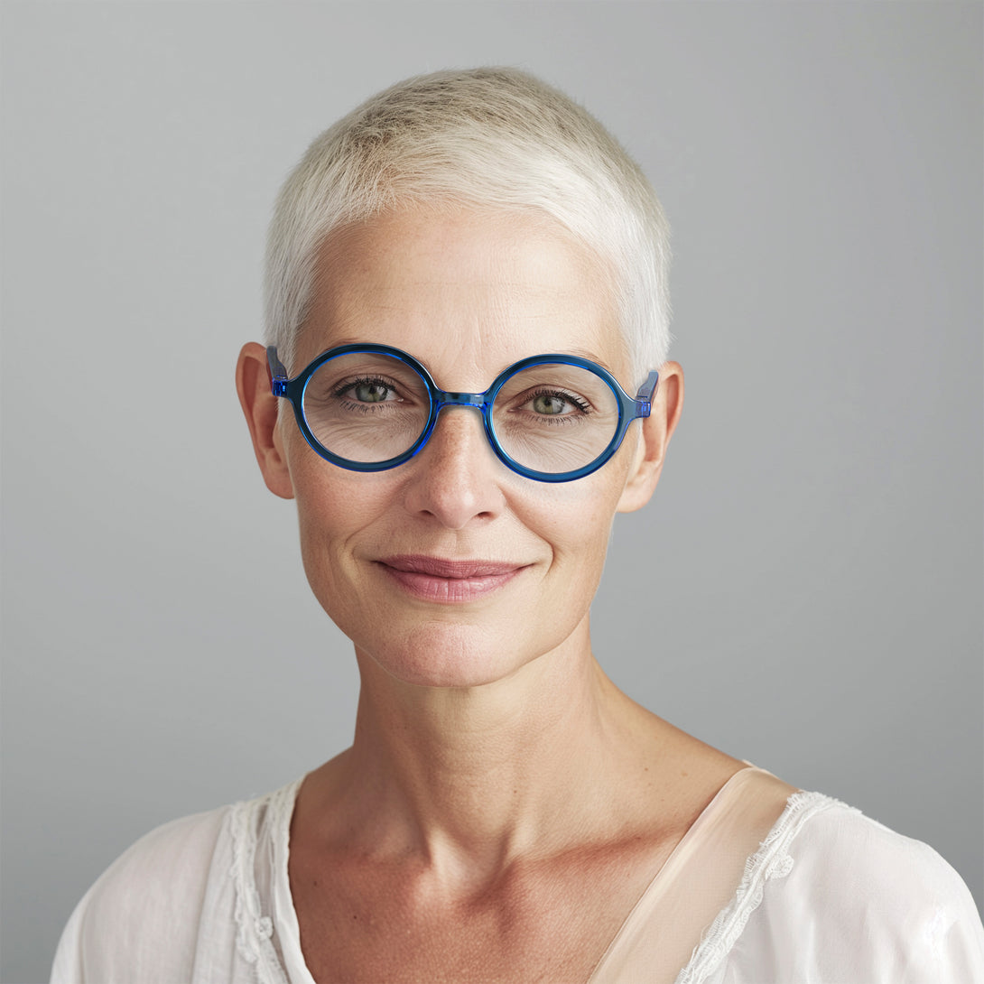 Female model - Artist Reading Glasses in transparent blue featuring an oversized circular frame and provide crystal clear vision. Available in a + 1, 1.5, 2, 2.5, 3 prescriptions.