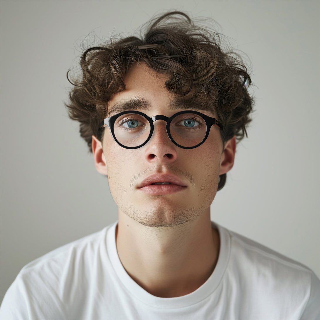 Male model - Graduate Blue Blocker Glasses in gloss black featuring a soft circle frame and the ability to protect your eyes from artificial blue light. Ideal for fashion accessories, screen time, office work, gaming, scrolling on a mobile, and watching TV. 
