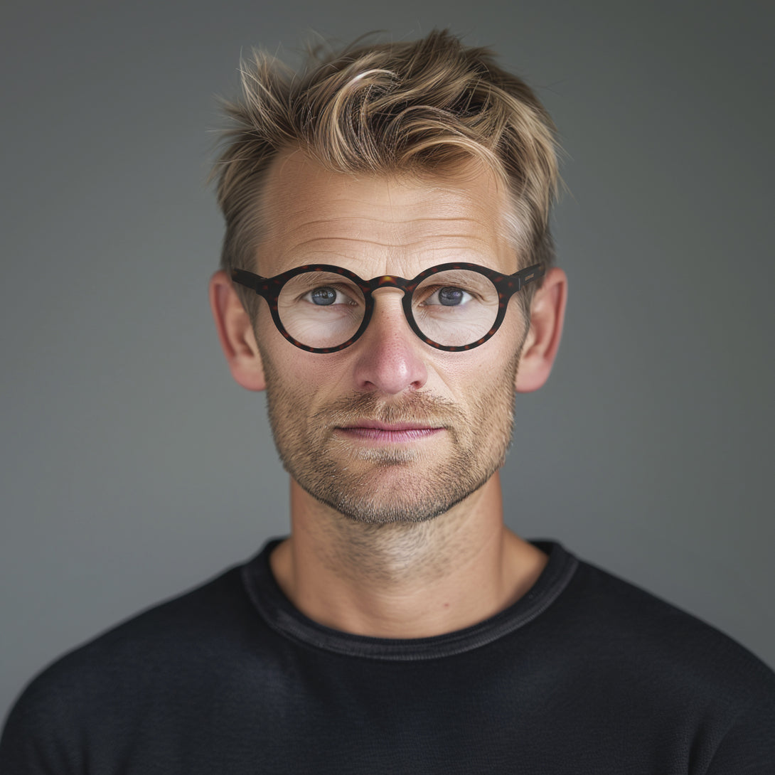 Male model - Graduate Blue Blocker Glasses in matt tortoiseshell featuring a soft circle frame and the ability to protect your eyes from artificial blue light. Ideal for fashion accessories, screen time, office work, gaming, scrolling on a mobile, and watching TV. 