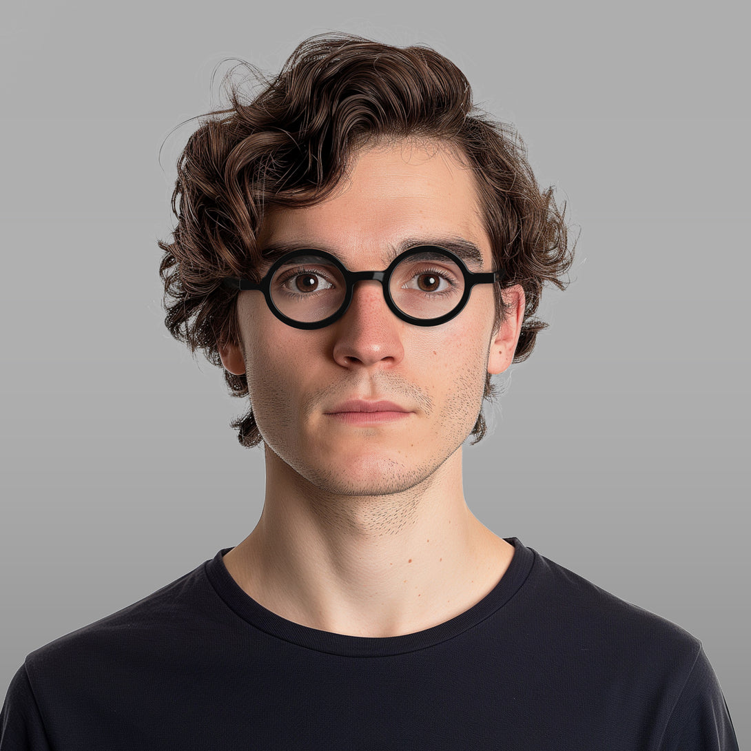 Male model - Moley Blue Blocker Glasses in gloss black featuring an eccentrically round frame and the ability to protect your eyes from artificial blue light. Ideal for fashion accessories, screen time, office work, gaming, scrolling on a mobile, and watching TV. 
