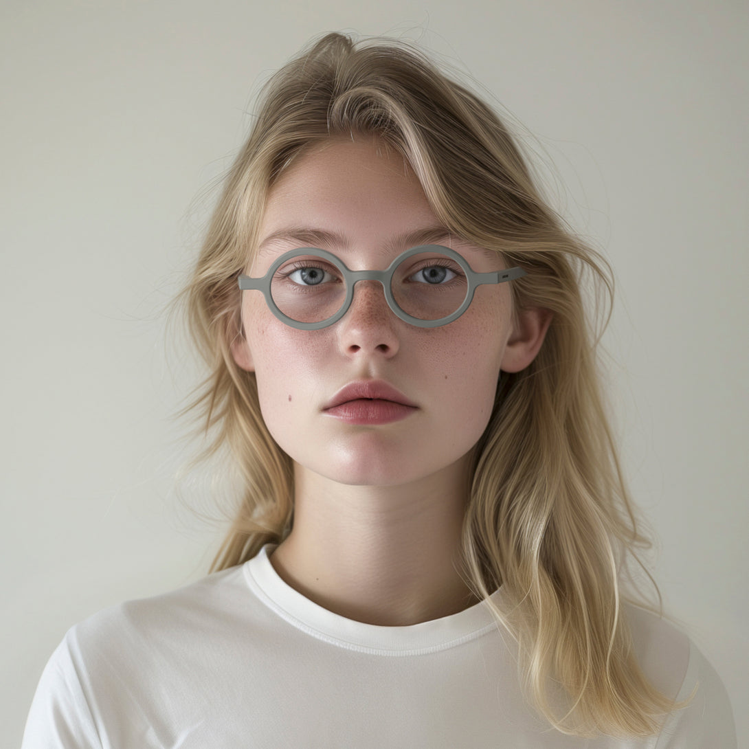 Female model - Moley Reading Glasses in matt grey featuring an eccentrically round frame and provide crystal clear vision. Available in a + 1, 1.5, 2, 2.5, 3 prescriptions.