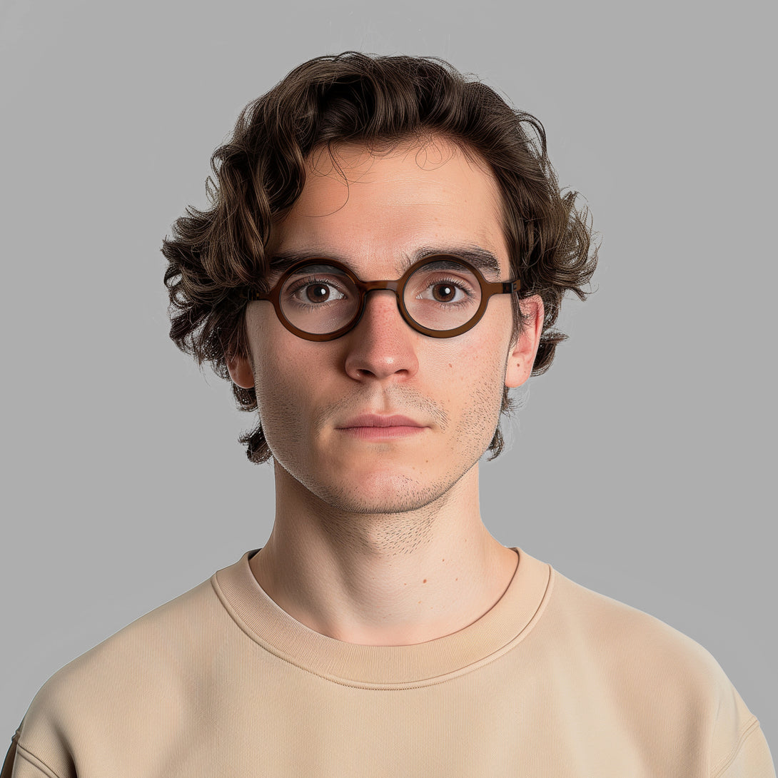 Male model - Moley Reading Glasses in transparent brown featuring an eccentrically round frame and provide crystal clear vision. Available in a + 1, 1.5, 2, 2.5, 3 prescriptions.