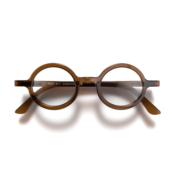 Front - Moley Reading Glasses in transparent brown featuring an eccentrically round frame and provide crystal clear vision. Available in a + 1, 1.5, 2, 2.5, 3 prescriptions.