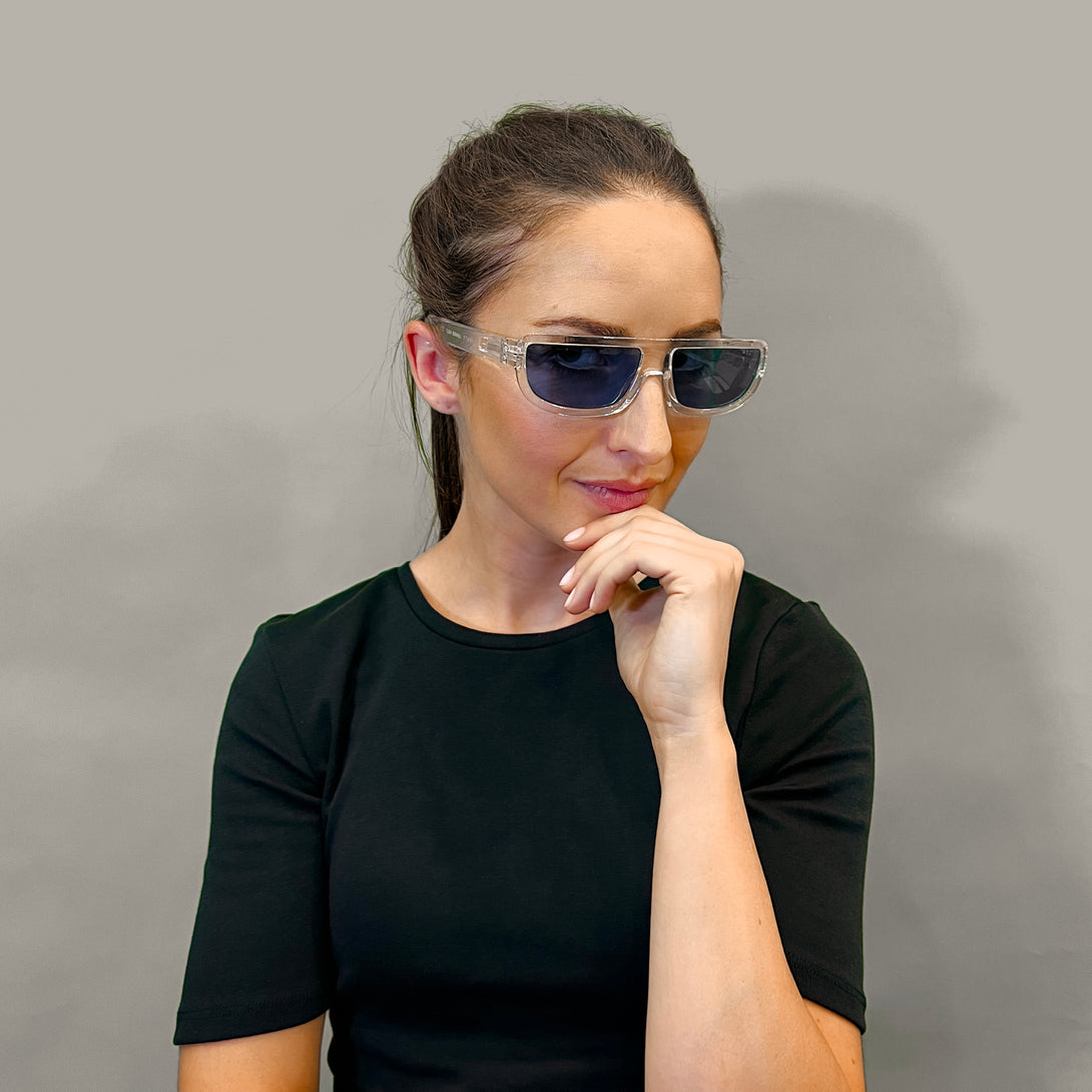 Female model - Feisty sunglasses in transparent featuring a utilitarian, straight top line frame and blue UV400 lenses. The finishing touch to every outfit while protecting your eyes. 