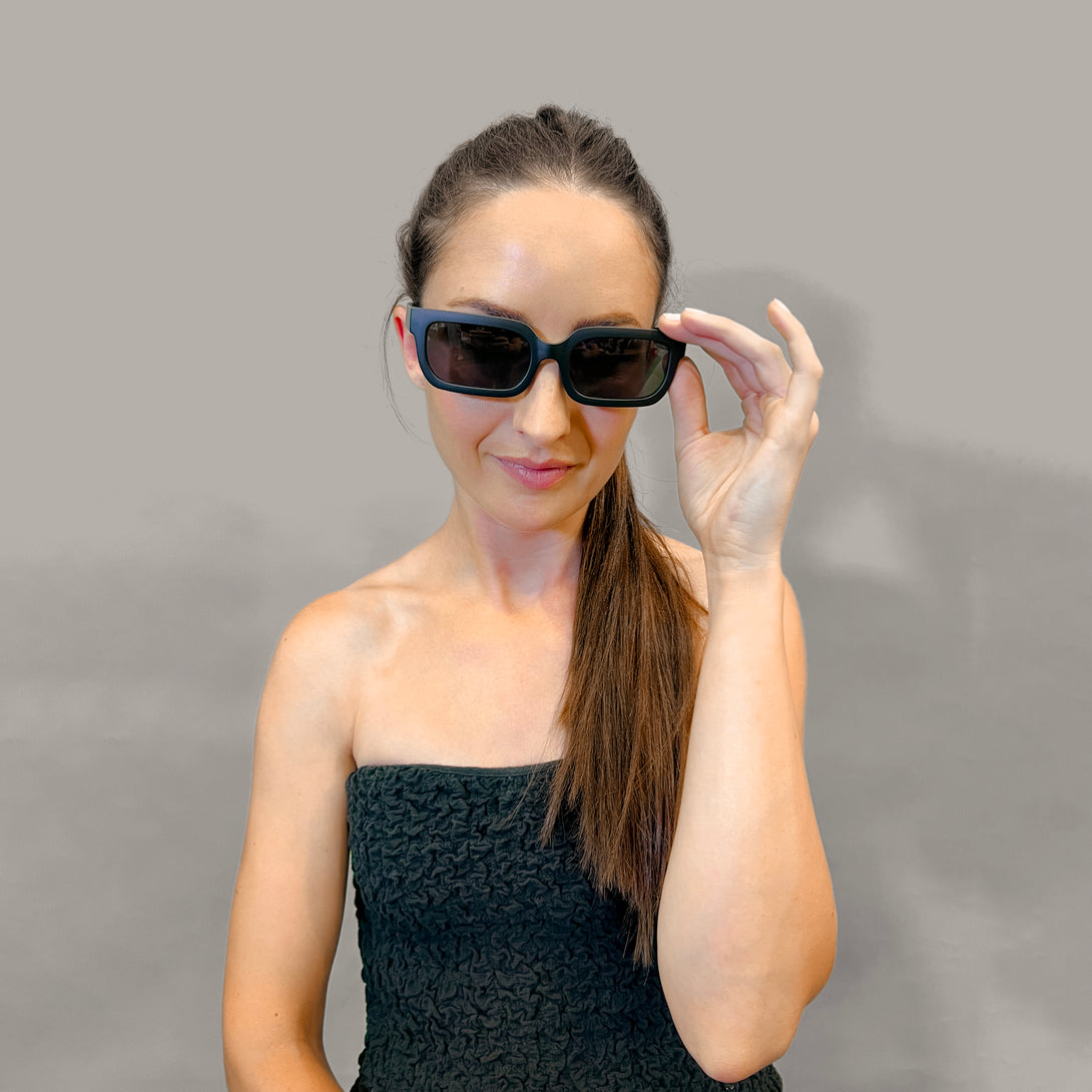 Female model 2 - Icy sunglasses in matt black featuring a bold rectangle frame and black UV400 lenses. The finishing touch to every outfit while protecting your eyes. 