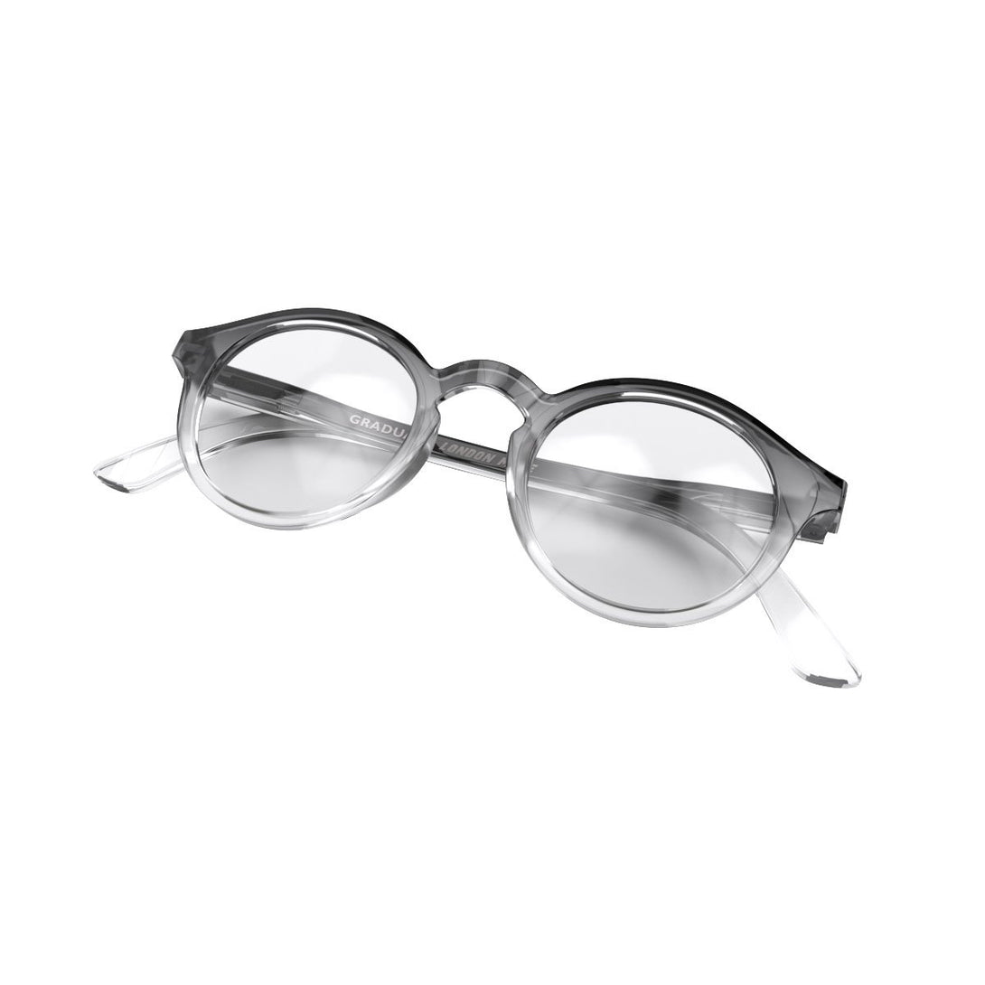 Skew folded - Graduate Reading Glasses in black transparent fade featuring a soft circle frame and provide crystal clear vision. Available in a + 1, 1.5, 2, 2.5, 3 prescriptions.