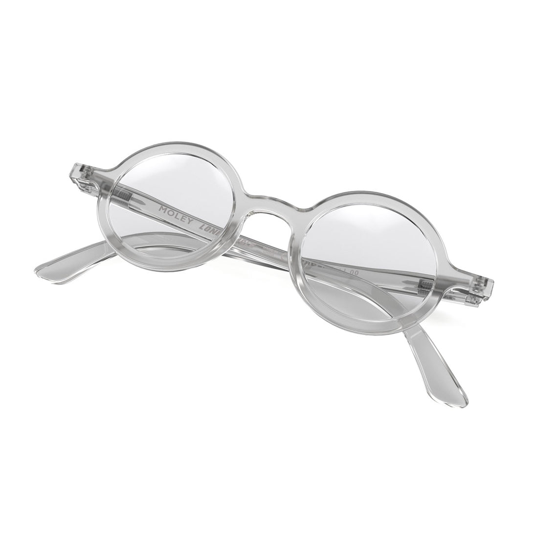 Front view folded of Moley Reading Glasses by London Mole with Transparent Frames.Folded skew - Moley Reading Glasses featuring an eccentrically round, transparent frame and provide crystal clear vision. Available in a + 1, 1.5, 2, 2.5, 3 prescriptions.