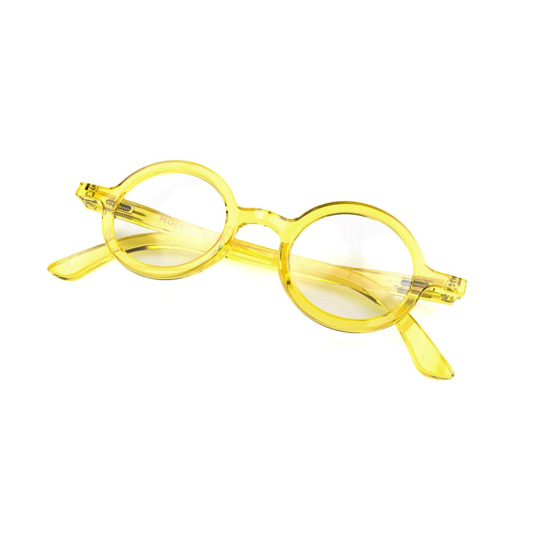 Closed skew - Moley Blue Blocker Glasses in transparent yellow featuring an eccentrically round frame and the ability to protect your eyes from artificial blue light. Ideal for fashion accessories, screen time, office work, gaming, scrolling on a mobile, and watching TV.  Moley Blue Blocker Glasses in Transparent Yellow